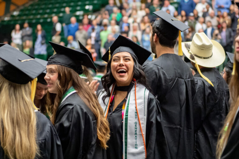 Student beams with joy as she looks up to the crowd at commencement.